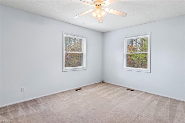 carpeted spare room featuring a textured ceiling and ceiling fan