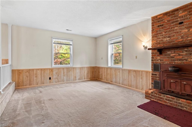 carpeted living room with wooden walls, a textured ceiling, and a healthy amount of sunlight