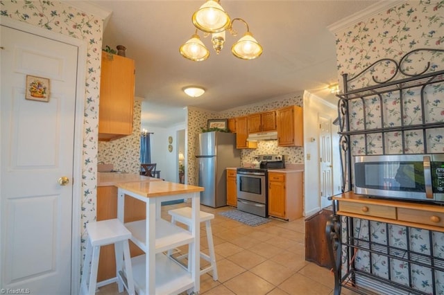 kitchen featuring a notable chandelier, appliances with stainless steel finishes, ornamental molding, under cabinet range hood, and wallpapered walls