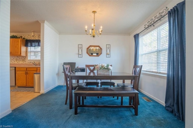 carpeted dining space with a sink, an inviting chandelier, ornamental molding, and a textured ceiling