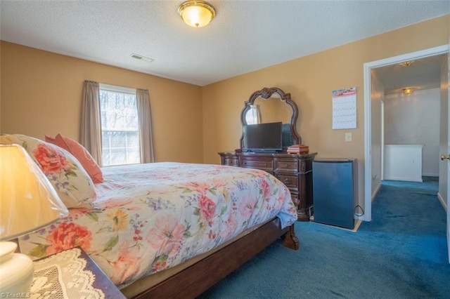 bedroom featuring a textured ceiling, carpet floors, fridge, and visible vents