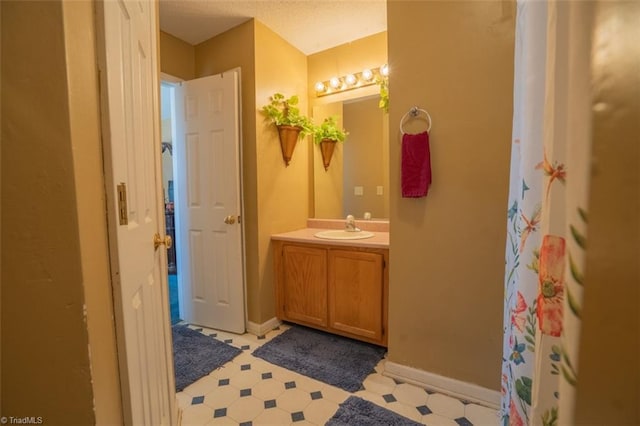 full bath featuring vanity, baseboards, and tile patterned floors