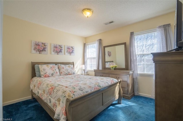 carpeted bedroom featuring baseboards, visible vents, and a textured ceiling