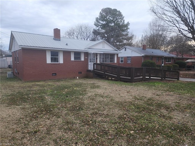 rear view of house with a deck, a yard, brick siding, and crawl space