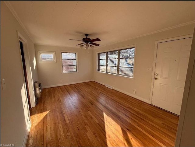 unfurnished living room with light wood-style floors, visible vents, crown molding, and baseboards