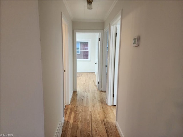 corridor with baseboards, crown molding, and light wood finished floors