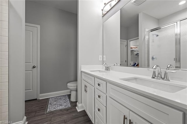 6624 Knob Creek Dr, Whitsett, NC 27377 - bathroom featuring double vanity, a stall shower, toilet, wood finished floors, and baseboards