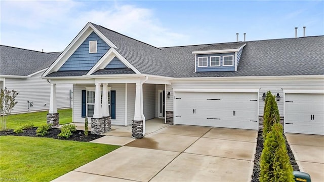 6624 Knob Creek Dr, Whitsett, NC 27377 - view of front of house with covered porch, driveway, a front lawn, stone siding, and roof with shingles