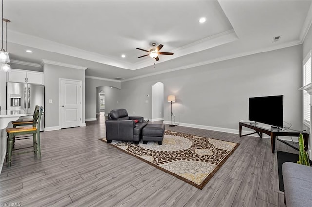 6624 Knob Creek Dr, Whitsett, NC 27377 - living room with arched walkways, a tray ceiling, a ceiling fan, wood finished floors, and recessed lighting