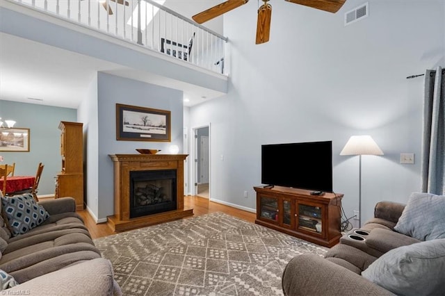 3702 Belfry Ct, Greensboro, NC 27410 - living area with wood finished floors, ceiling fan, a towering ceiling, a fireplace with raised hearth, and baseboards