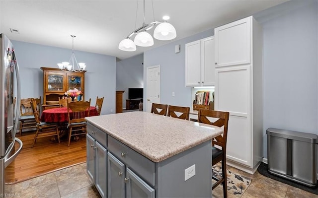 3702 Belfry Ct, Greensboro, NC 27410 - kitchen with a chandelier, gray cabinets, freestanding refrigerator, a kitchen island, and light countertops