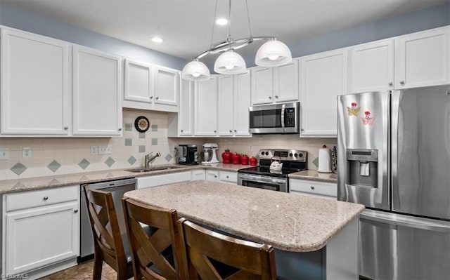 3702 Belfry Ct, Greensboro, NC 27410 - kitchen featuring appliances with stainless steel finishes, a sink, a breakfast bar, white cabinetry, and backsplash