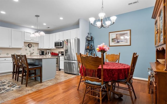 3702 Belfry Ct, Greensboro, NC 27410 - dining room featuring a chandelier, recessed lighting, light wood-type flooring, and baseboards