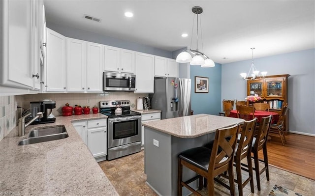 3702 Belfry Ct, Greensboro, NC 27410 - kitchen featuring appliances with stainless steel finishes, a sink, a center island, a breakfast bar, and decorative backsplash