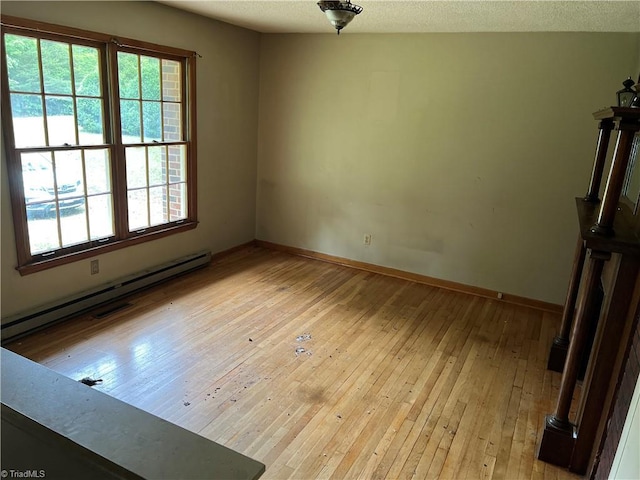 unfurnished room featuring light wood-type flooring and baseboard heating