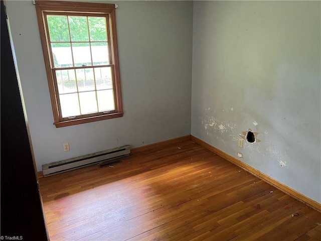 spare room featuring a baseboard radiator and hardwood / wood-style floors