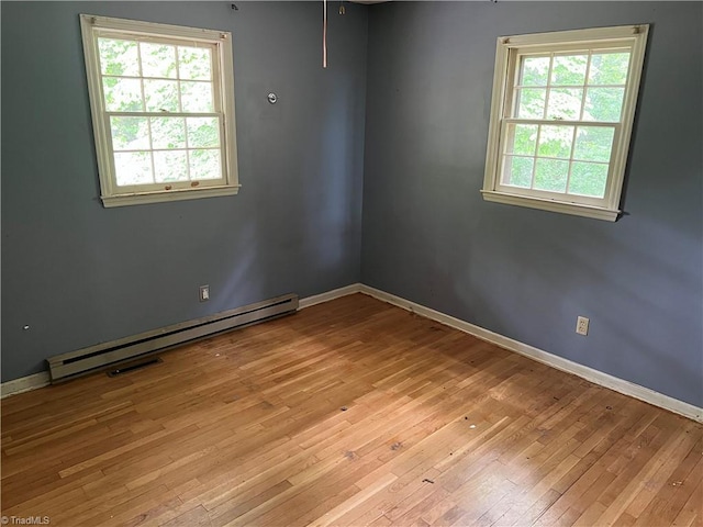 empty room with light hardwood / wood-style floors and a baseboard heating unit