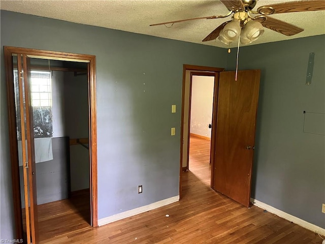 unfurnished bedroom featuring ceiling fan, a closet, a textured ceiling, and wood-type flooring