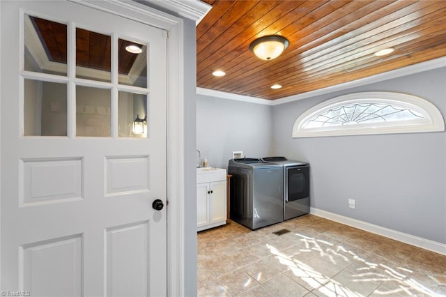 laundry room featuring baseboards, washing machine and clothes dryer, cabinet space, wood ceiling, and crown molding