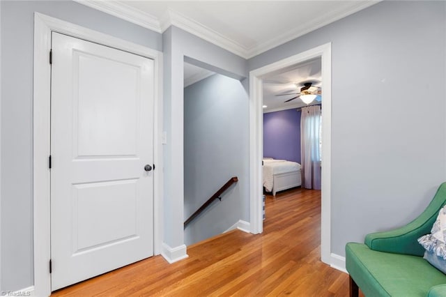 hall with baseboards, an upstairs landing, ornamental molding, and light wood finished floors