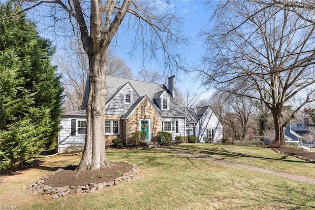 cape cod house with a front lawn, stone siding, and a chimney