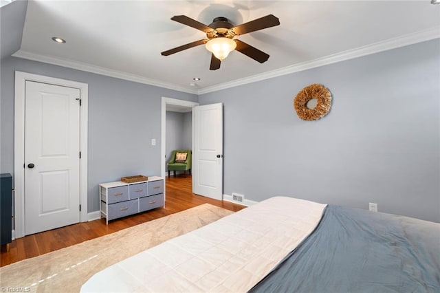 bedroom with baseboards, wood finished floors, and crown molding