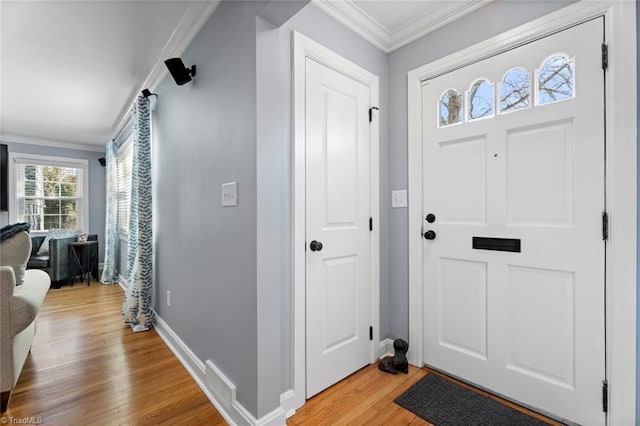 entrance foyer featuring light wood-type flooring, baseboards, visible vents, and ornamental molding