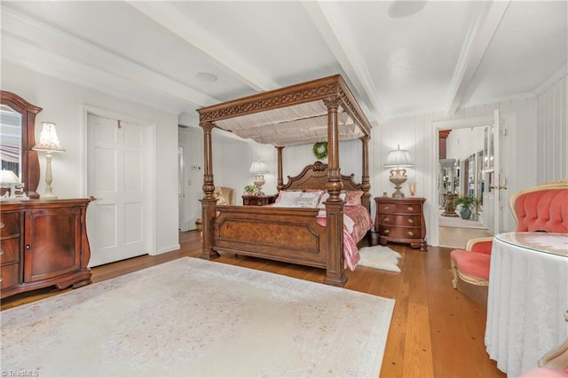 bedroom featuring beamed ceiling, multiple windows, hardwood / wood-style floors, and ornamental molding