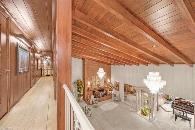 hallway featuring wood walls, lofted ceiling with beams, a chandelier, and wood ceiling