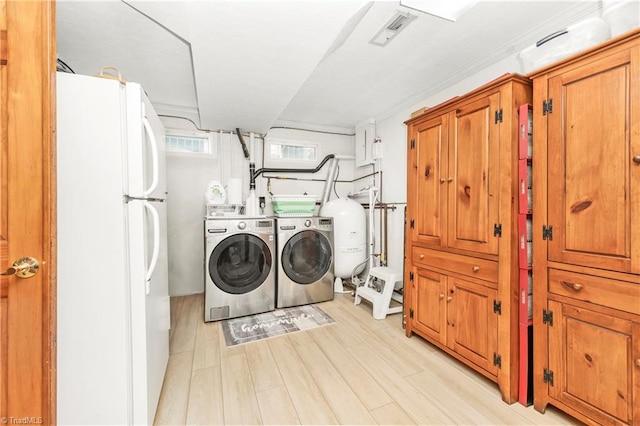 laundry area with light hardwood / wood-style floors and washer and dryer