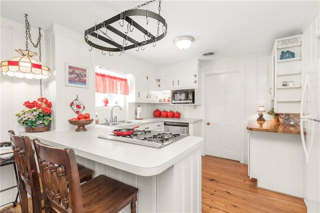 kitchen featuring light wood-type flooring, sink, a kitchen bar, appliances with stainless steel finishes, and kitchen peninsula