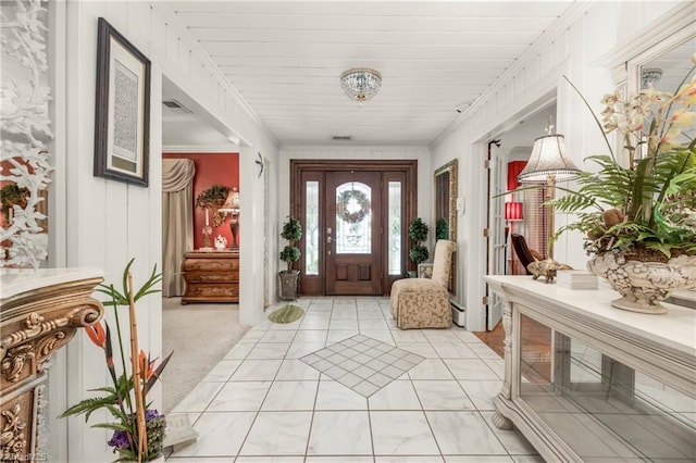 carpeted foyer with ornamental molding