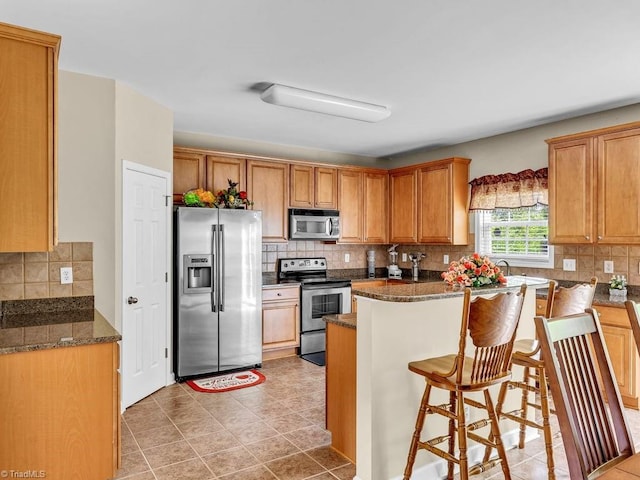 kitchen featuring appliances with stainless steel finishes, a kitchen bar, and decorative backsplash