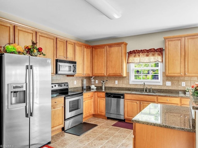 kitchen with sink, backsplash, stainless steel appliances, and dark stone counters