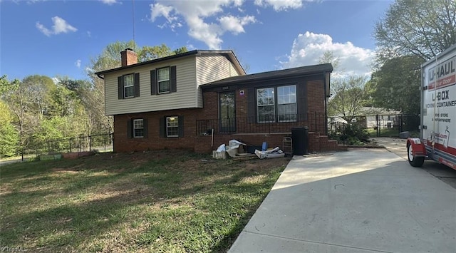 view of front of house featuring brick siding, a front lawn, fence, and a chimney