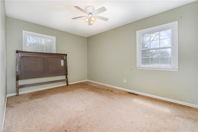 carpeted spare room with plenty of natural light, baseboards, and ceiling fan