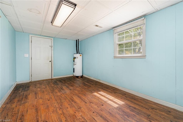 basement featuring wood finished floors, baseboards, visible vents, and water heater
