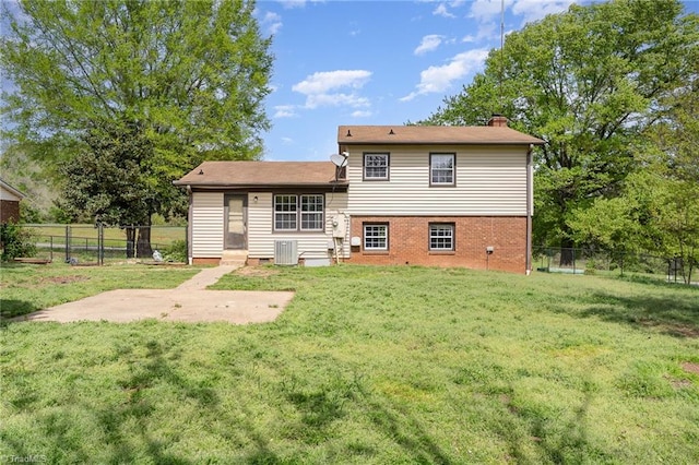 back of property featuring central AC, entry steps, a lawn, fence, and brick siding