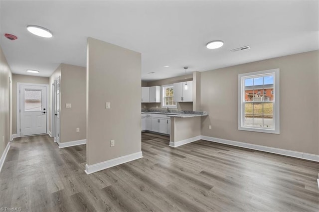 kitchen featuring visible vents, white cabinetry, baseboards, and wood finished floors