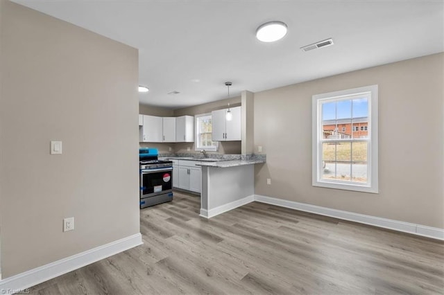 kitchen featuring baseboards, visible vents, stainless steel range with gas cooktop, white cabinetry, and light wood-type flooring