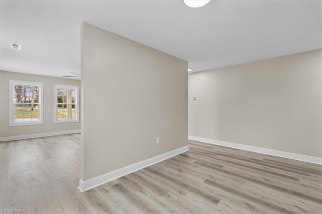 unfurnished room featuring visible vents, wood finished floors, and baseboards