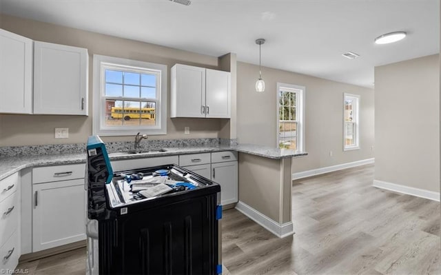 kitchen with visible vents, stove, light wood-style flooring, and white cabinetry