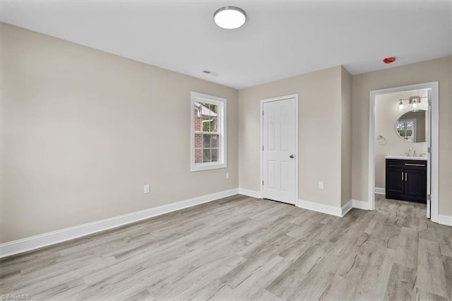 unfurnished living room featuring a sink, visible vents, baseboards, and light wood-style flooring