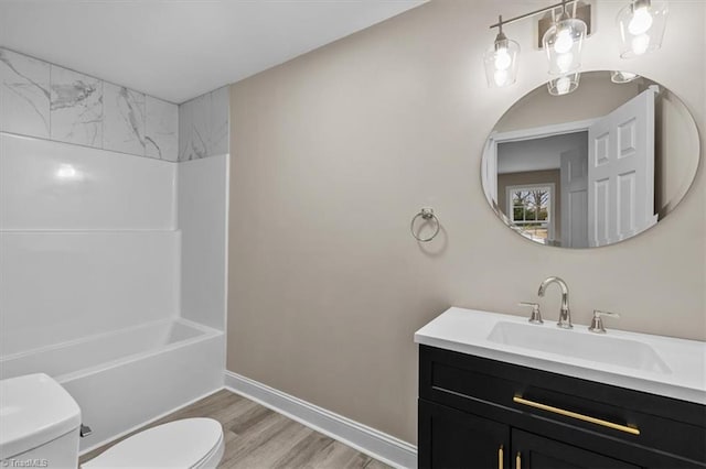 full bath featuring vanity, washtub / shower combination, wood finished floors, baseboards, and toilet