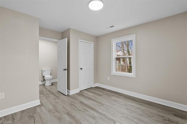 unfurnished bedroom with visible vents, baseboards, a closet, and wood finished floors