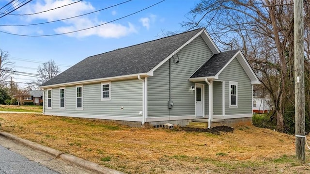 view of side of property with a yard and roof with shingles