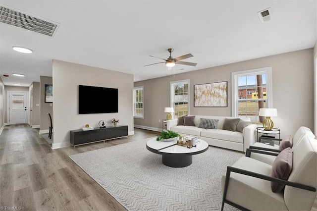 living area featuring visible vents, ceiling fan, baseboards, and wood finished floors