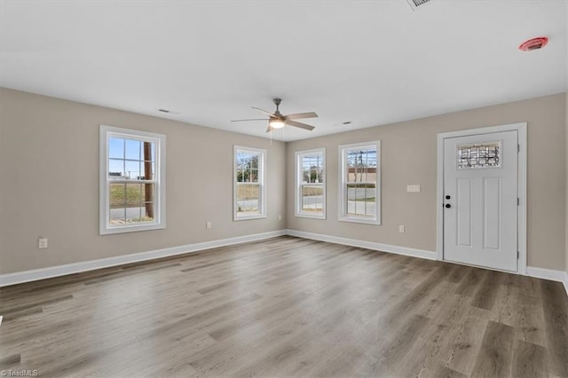 interior space featuring ceiling fan, baseboards, plenty of natural light, and wood finished floors