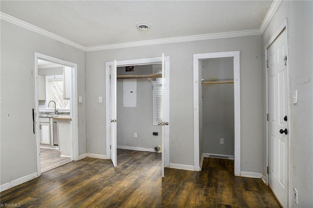 unfurnished bedroom featuring a textured ceiling, a sink, wood finished floors, visible vents, and ornamental molding