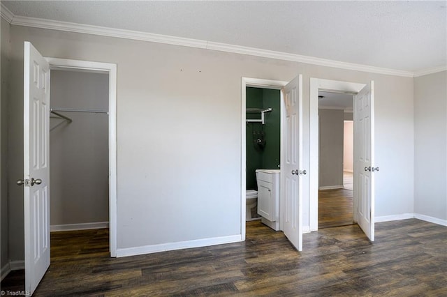 unfurnished bedroom with a walk in closet, dark wood-style flooring, a closet, ornamental molding, and baseboards